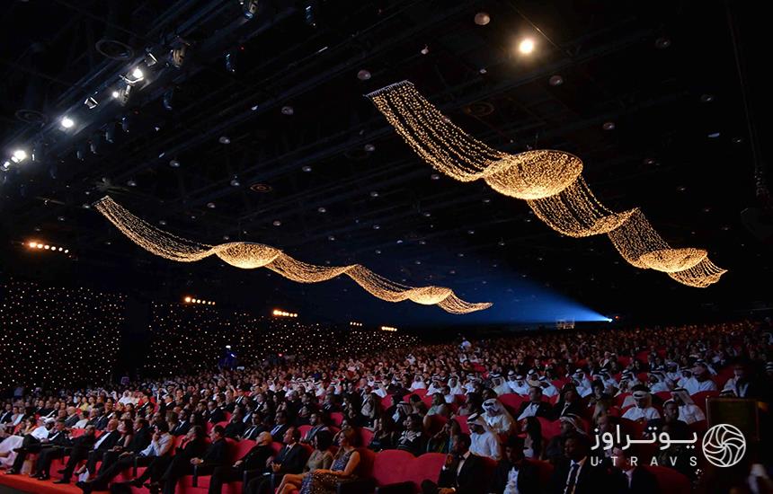 یک سالن سینمای تاریک و آماده نمایش فیلم در دبی که سقفش با لامپ‌های ریسه‌ای زردرنگ تزیین شده‌است.